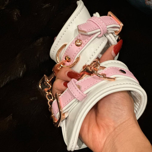 Image des Menottes en Cuir Couleur Blanc et Rose portées sur fond de Fourrure Noir