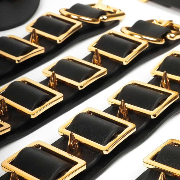 Coffret BDSM ouvert en cuir noir avec intérieur rouge, présentant un ensemble d’accessoires assortis comprenant menottes, sangles, cravaches et chaînes, disposés de manière ordonnée dans une esthétique luxueuse.