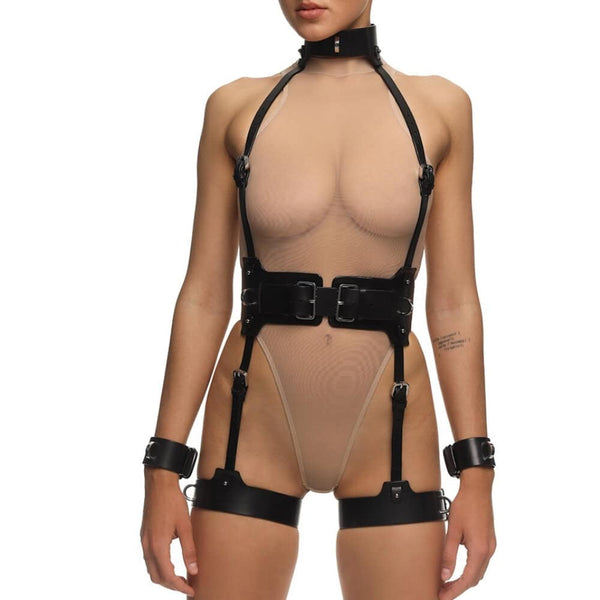 Full Set REVNA signé Anoeses : ensemble bondage en cuir noir avec harnais, collier, ceinture et menottes de cuisse reliées par des sangles – silhouette graphique et fétiche au style affirmé.