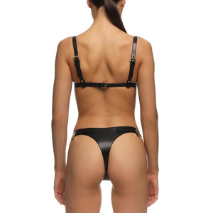 Soutien-gorge ANOESIS en cuir noir avec armatures, sangles réglables et finitions métalliques dorées, porté avec un string assorti sur fond blanc.