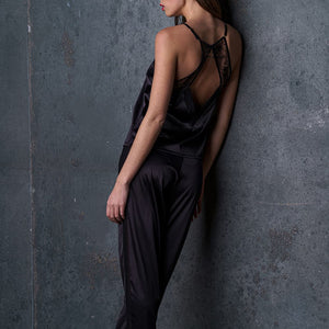 Le pantalon satin Nuit à Broadway porté par une femme, avec une ceinture froncée pour un confort optimal. Ses poches plaquées et ses bandes latérales lui donnent un look moderne et raffiné, idéal pour un ensemble homewear sexy.