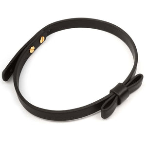Set BDSM en cuir noir composé de liens ajustables avec anneaux dorés, d’un bandeau en tissu satiné et d’une plume noire montée sur manche doré, présenté sur fond blanc dans une esthétique épurée.