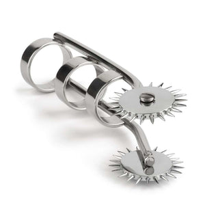 Roulette de Wartenberg à doigts en acier poli avec deux roues crantées et anneaux de maintien, présentée sur fond blanc dans une esthétique minimaliste et professionnelle.