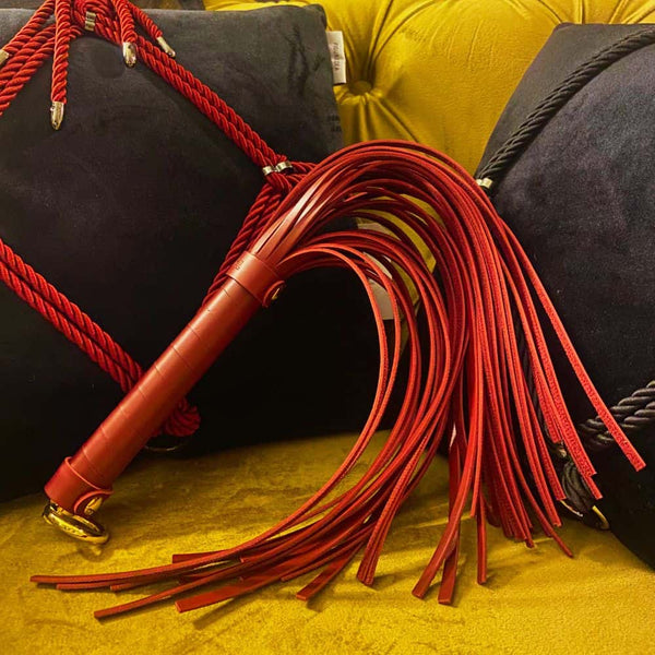 Fouet rouge BDSM posé sur un fauteuil.