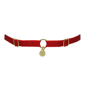 Ici vous pouvez voir le BRIGADE MONDAINE GIFT WRAP RED. Ce collier est fait d’une bande rouge. 2 détails pour régler les bandes se trouvent à droite et à gauche. Au milieu, la bande est séparée par un anneau plaqué or avec un pendentif où il est inscrit « BM ».