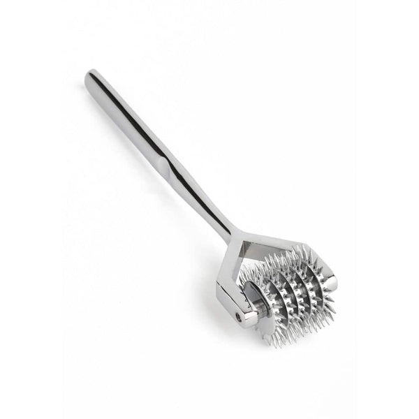 Roulette de Wartenberg en acier inoxydable brillant avec roulettes dentelées, design médical revisité, présentée par Brigade Mondaine Paris sur fond clair.