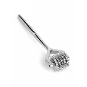 Roulette de Wartenberg en acier inoxydable brillant avec roulettes dentelées, design médical revisité, présentée par Brigade Mondaine Paris sur fond clair.
