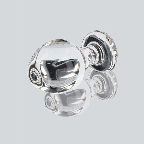 Plug anal en verre transparent poli à finition brillante, forme sphérique avec base évasée, présenté sur fond blanc, sélection Brigade Mondaine Paris.