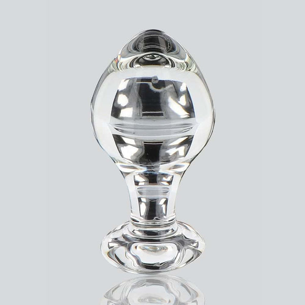 Plug anal en verre transparent poli à finition brillante, forme sphérique avec base évasée, présenté sur fond blanc, sélection Brigade Mondaine Paris.