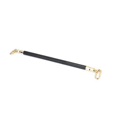 Barre d’écartement en cuir noir embossé peau d’autruche avec clips à dégagement rapide et finitions dorées. Accessoire BDSM de contrôle élégant.