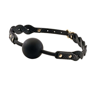 Bâillon boule BDSM composé d’une boule noire mate et de sangles en cuir noir texturé avec rivets et bouclerie dorée, présenté sur fond sombre dans une mise en scène élégante.
