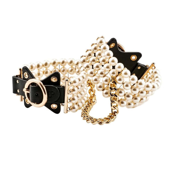 Entraves de chevilles en cuir noir ornées de perles et reliées par une chaîne dorée, portées sur modèle, proposées par Brigade Mondaine Paris.