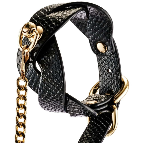 Modèle portant un collier BDSM noir texturé avec chaîne dorée et dragonne assortie, accessoire de contrainte proposé par Brigade Mondaine Paris.