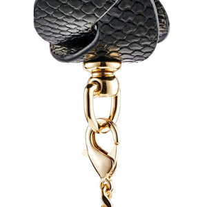 Modèle portant un collier BDSM noir texturé avec chaîne dorée et dragonne assortie, accessoire de contrainte proposé par Brigade Mondaine Paris.