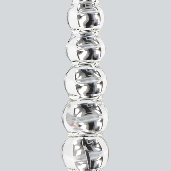 Dildo en verre transparent composé de formes sphériques alignées, présenté verticalement sur fond blanc, avec une finition lisse et brillante.