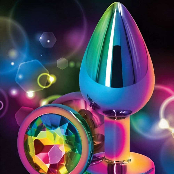 Plug anal en cristal multicolore avec base décorative en forme de cœur facetté, présenté sur fond sombre avec effets lumineux et reflets irisés.