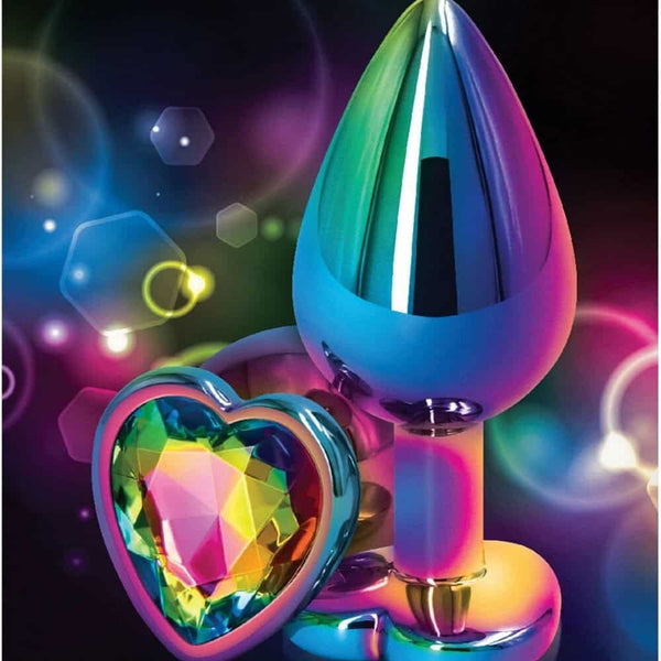 Plug anal en cristal multicolore avec base décorative en forme de cœur facetté, présenté sur fond sombre avec effets lumineux et reflets irisés.