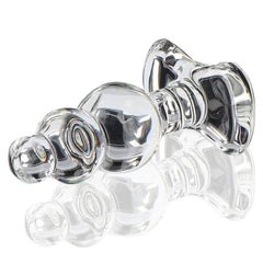 Plug anal en verre transparent à forme facettée avec base évasée, présenté sur fond clair, finition brillante, sélection Brigade Mondaine Paris.