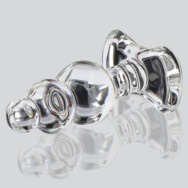Plug anal en verre transparent à forme facettée avec base évasée, présenté sur fond clair, finition brillante, sélection Brigade Mondaine Paris.