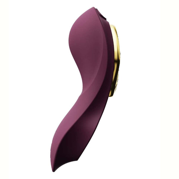 Vibromasseur portable de couleur prune avec détails dorés, design ergonomique et commandes intégrées, présenté sur fond blanc, sélection Brigade Mondaine Paris.