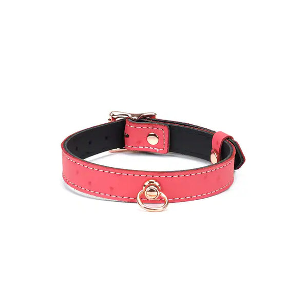 Choker O en cuir rose cerisier, embossé peau d’autruche, avec anneau central. Finition métal or rose, ajustable avec boucle dorée. Accessoire fétichiste chic pour marquer l’appartenance.