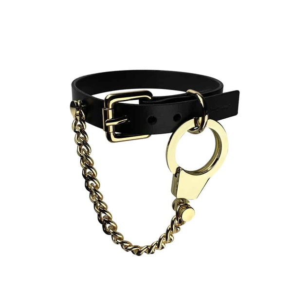 Collier Menottes chaines et cuir de la marque ELF ZHOU LONDON. le collier est attaché autour du cou du mannequin. La partie en cuir du collier est attachée et la chaine en or rattachée au collier par la menotte en or pend.