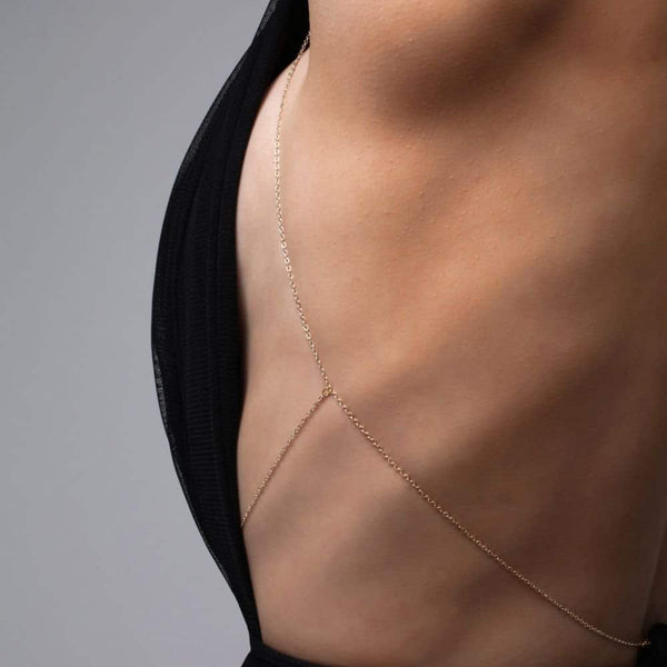 Détail d'une Photo d'une Femme de Côté portant un Bijou de Buste Doré avec bijoux Swarovski et Croix avec une Tenue Noire