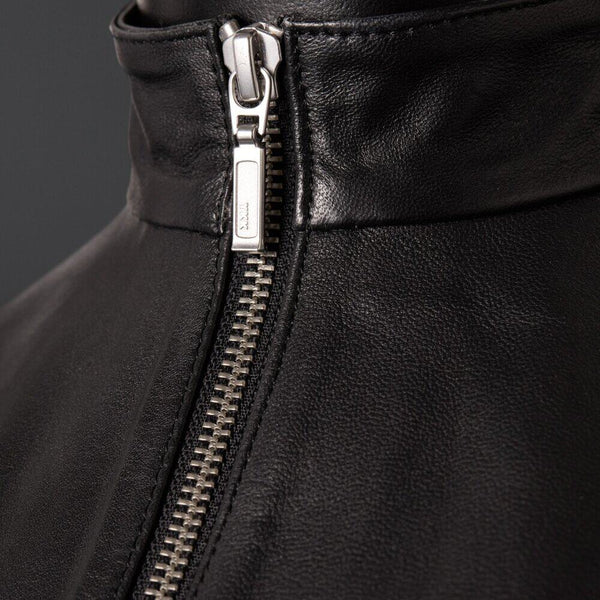 Top en cuir de mouton noir zippé à col montant zip central et dos entièrement ouvert à nouer La coupe est droite, couvrante. La matière, elle, ne cache rien.