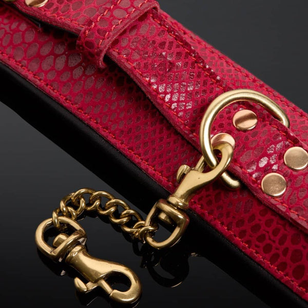 Menottes en cuir embossé serpent rouge avec finitions dorées et intérieur en cuir de veau noir, offrant confort et maintien avec un design visuellement saisissant.