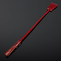 Cravache en vernis rouge HOUSE OF SXN avec manche rigide et extrémité plate, accessoire BDSM haut de gamme proposé par Brigade Mondaine Paris.