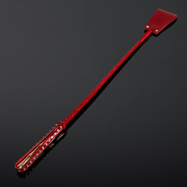 Cravache en vernis rouge HOUSE OF SXN avec manche rigide et extrémité plate, accessoire BDSM haut de gamme proposé par Brigade Mondaine Paris.