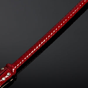 Cravache en vernis rouge HOUSE OF SXN avec manche rigide et extrémité plate, accessoire BDSM haut de gamme proposé par Brigade Mondaine Paris.