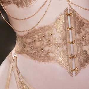Le corset taille AIMÉE est une pièce artisanale raffinée, confectionnée à la main avec de la dentelle Leavers française en or rosé et un tulle ultra-transparent. Il est doté d'anneaux dorés et d'un laçage au dos, permettant un ajustement personnalisé. Le devant présente des crochets et œillets dorés, cousus avec précision, et la base structurée avec des baleines souples sculpte une silhouette parfaite. Les bretelles doubles amovibles ajoutent confort et flexibilité. À porter en serre-taille ou en porte-jarr