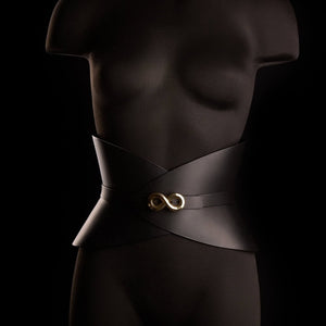 Corset ceinture HUDIA IINFYNII en cuir noir avec fermoir métallique infini porté sur un tailleur noir, accessoire structurant et graphique proposé par Brigade Mondaine Paris