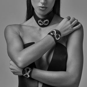 Choker SASKIA IINFYNII en cuir noir avec symbole métallique, collier ras de cou graphique porté sur buste féminin, accessoire de corps sélection Brigade Mondaine Paris