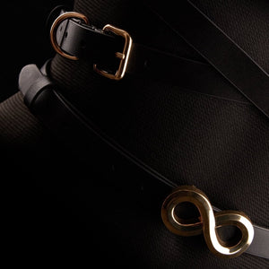 Harnais TRISCA IINFYNII en sangles noires avec boucles dorées et détail central, accessoire structurant porté sur le buste proposé par Brigade Mondaine Paris