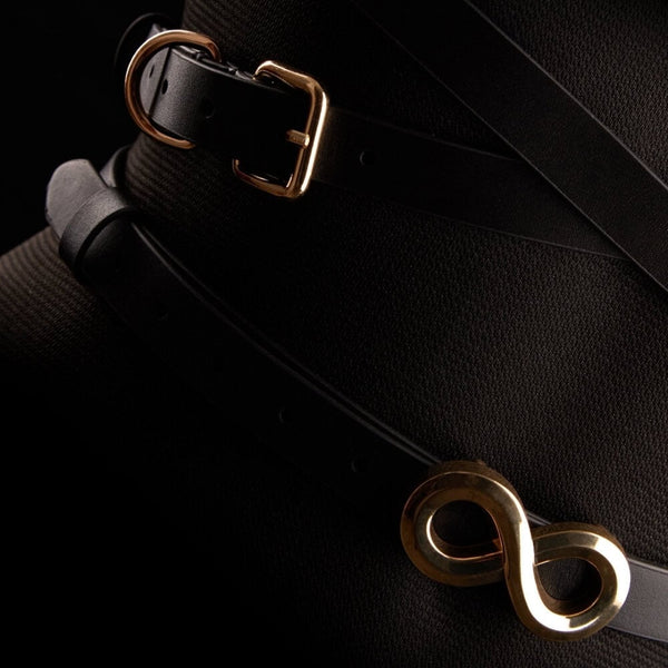 Harnais TRISCA IINFYNII en sangles noires avec boucles dorées et détail central, accessoire structurant porté sur le buste proposé par Brigade Mondaine Paris