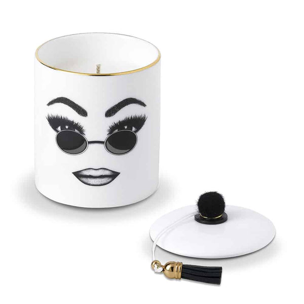 Une bougie parfumée en porcelaine chinoise blanche arbore un visage confiant, soigneusement tracé en feutrine. Ce visage exprime la la confiance en soi, le confort et le cool avec des lunettes de soleils rondes et un maquillage parfaitement exécuté
