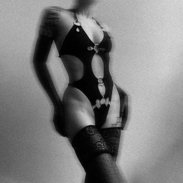 Lingerie érotique en jersey doux et velours noir, design audacieux avec découpes graphiques et anneaux métalliques. Bretelles ajustables pour un maintien confortable et sensuel.