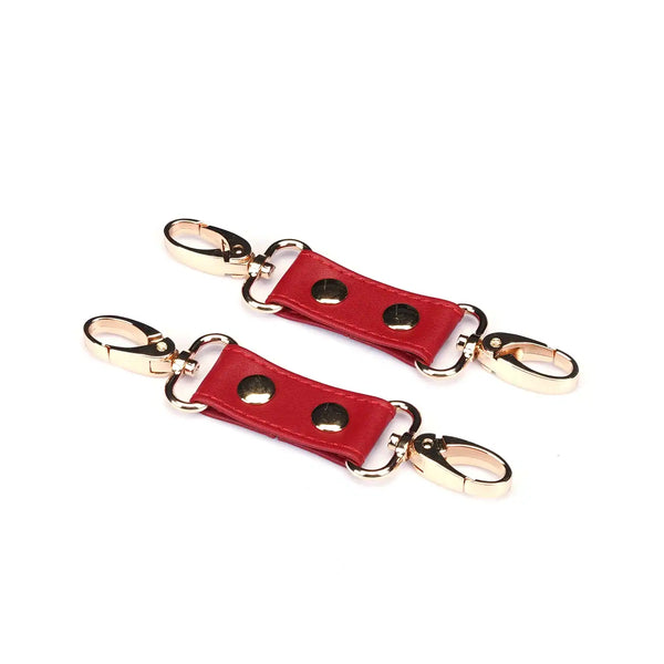 Hogtie Crimson Desire de la marque Liebe Seele, composé de sangles en cuir rouge reliées par un anneau central et des mousquetons dorés, présenté sur fond clair dans l’univers Brigade Mondaine Paris.