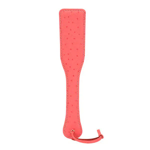 Paddle en cuir rose cerisier LIEBE SEELE, embossée peau d'autruche, légère et maniable. Design glamour et fonction redoutable pour des jeux BDSM intenses. Dragonne pour rangement discret.
