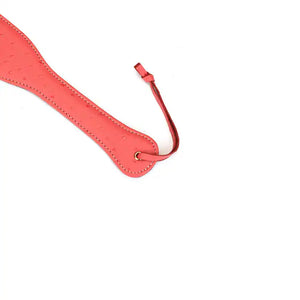 Paddle en cuir rose cerisier LIEBE SEELE, embossée peau d'autruche, légère et maniable. Design glamour et fonction redoutable pour des jeux BDSM intenses. Dragonne pour rangement discret.