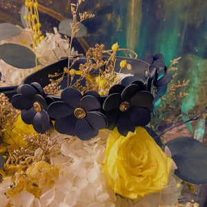 Collier en cuir au design fleur posé sur des fleurs.