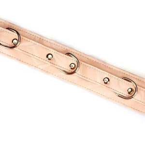 Collier de bondage Pink Boudoir Amor en similicuir vegan rose et noir. Finitions dorées, trois anneaux en D pour fixation. Avec laisse en chaîne dorée, élégant et ajustable pour une domination raffinée.