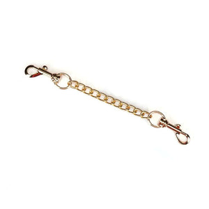 Menottes Boudoir Amor en similicuir vegan rose pastel et noir. Finitions dorées, anneau en D pour fixation. Boucles ajustables et clips à dégagement rapide pour sécurité et confort. Idéales pour des jeux de soumission élégants.