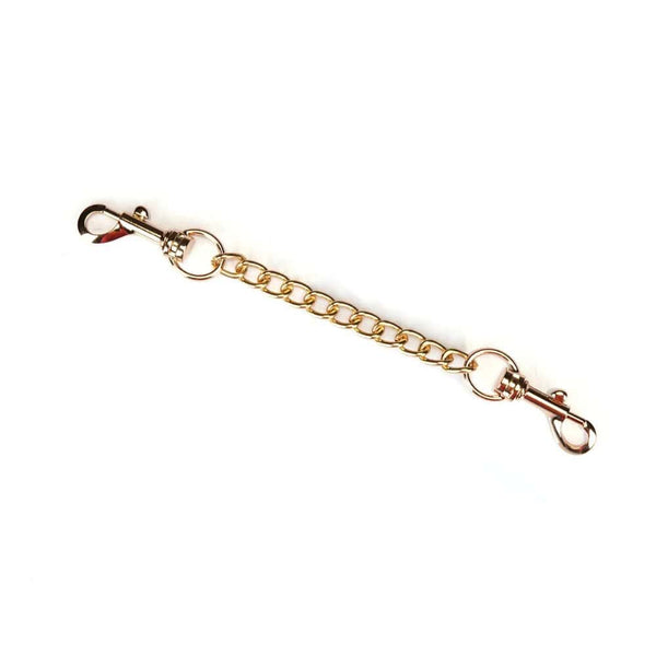 Menottes Boudoir Amor en similicuir vegan rose pastel et noir. Finitions dorées, anneau en D pour fixation. Boucles ajustables et clips à dégagement rapide pour sécurité et confort. Idéales pour des jeux de soumission élégants.