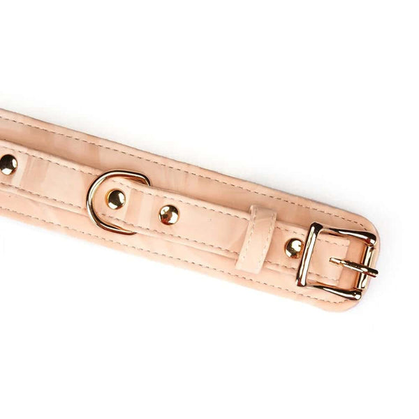 Menottes Boudoir Amor en similicuir vegan rose pastel et noir. Finitions dorées, anneau en D pour fixation. Boucles ajustables et clips à dégagement rapide pour sécurité et confort. Idéales pour des jeux de soumission élégants.