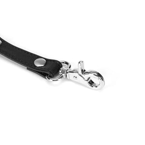 Hogtie en cuir noir avec clips métalliques argentés de la collection Black Bond, pour une soumission totale. Accessoire BDSM durable et efficace, conçu à partir de matériaux recyclés.