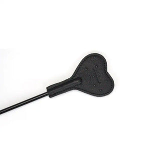 Cravache en cuir noir embossé façon autruche avec marque en forme de cœur. Accessoire BDSM léger et maniable avec manche texturé et finitions dorées.