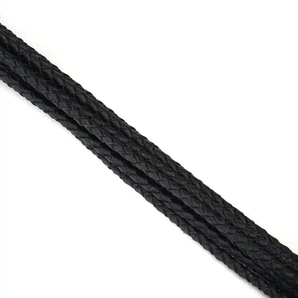 Fouet à neuf queues en cuir noir tressé avec pointes de cuir. Accessoire BDSM léger et maniable, avec prise ferme et boucle de suspension discrète.